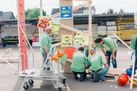 Event-Teilnehmer grünen T-Shirts arbeiten an einem Teil der großen Kettenreaktion.