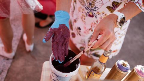 Eine Frau streicht sich violette Farbe auf ihren Handschuh.