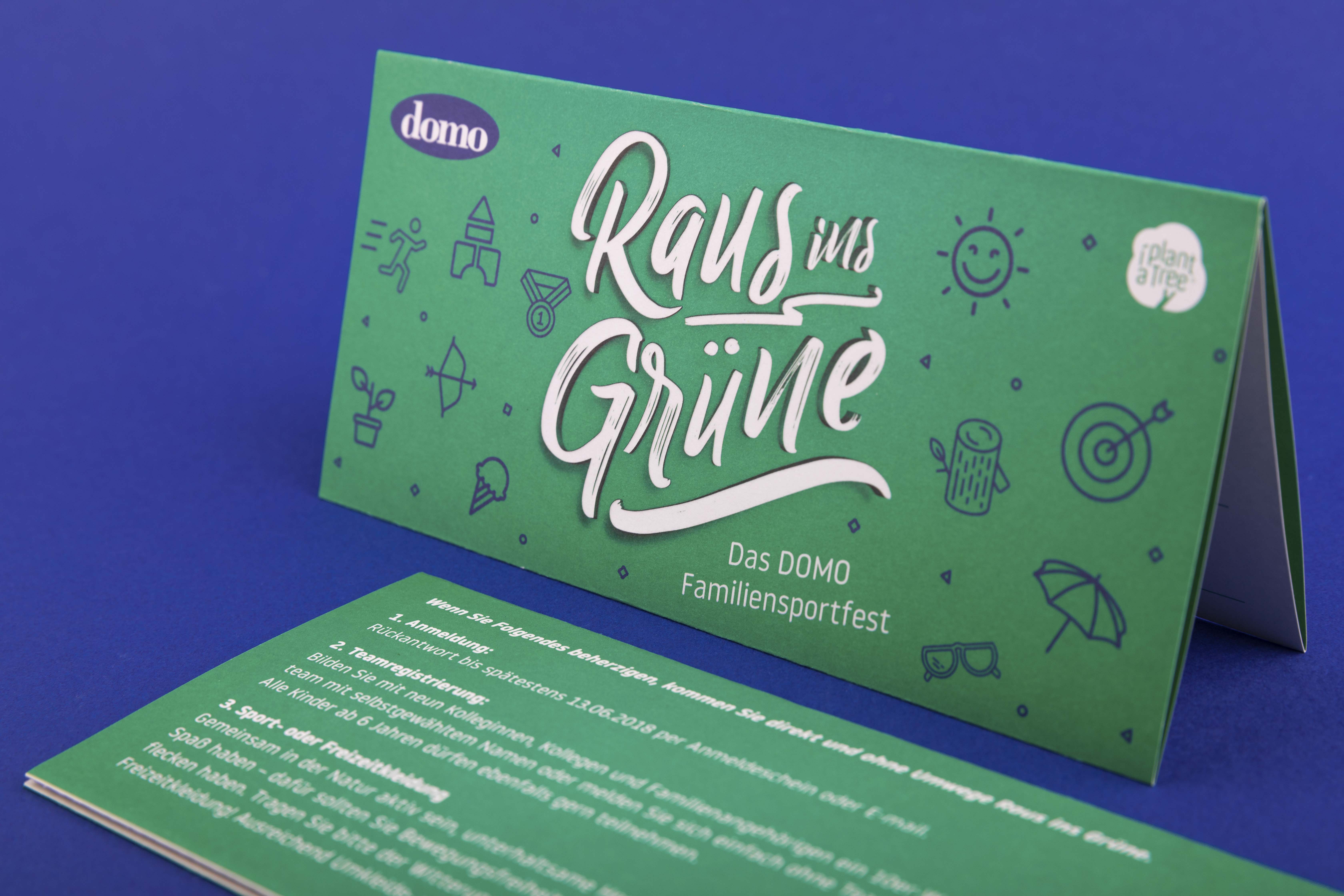 Save-the-Date Karte im Event-Design stehend vor einem blauen Hintergrund.