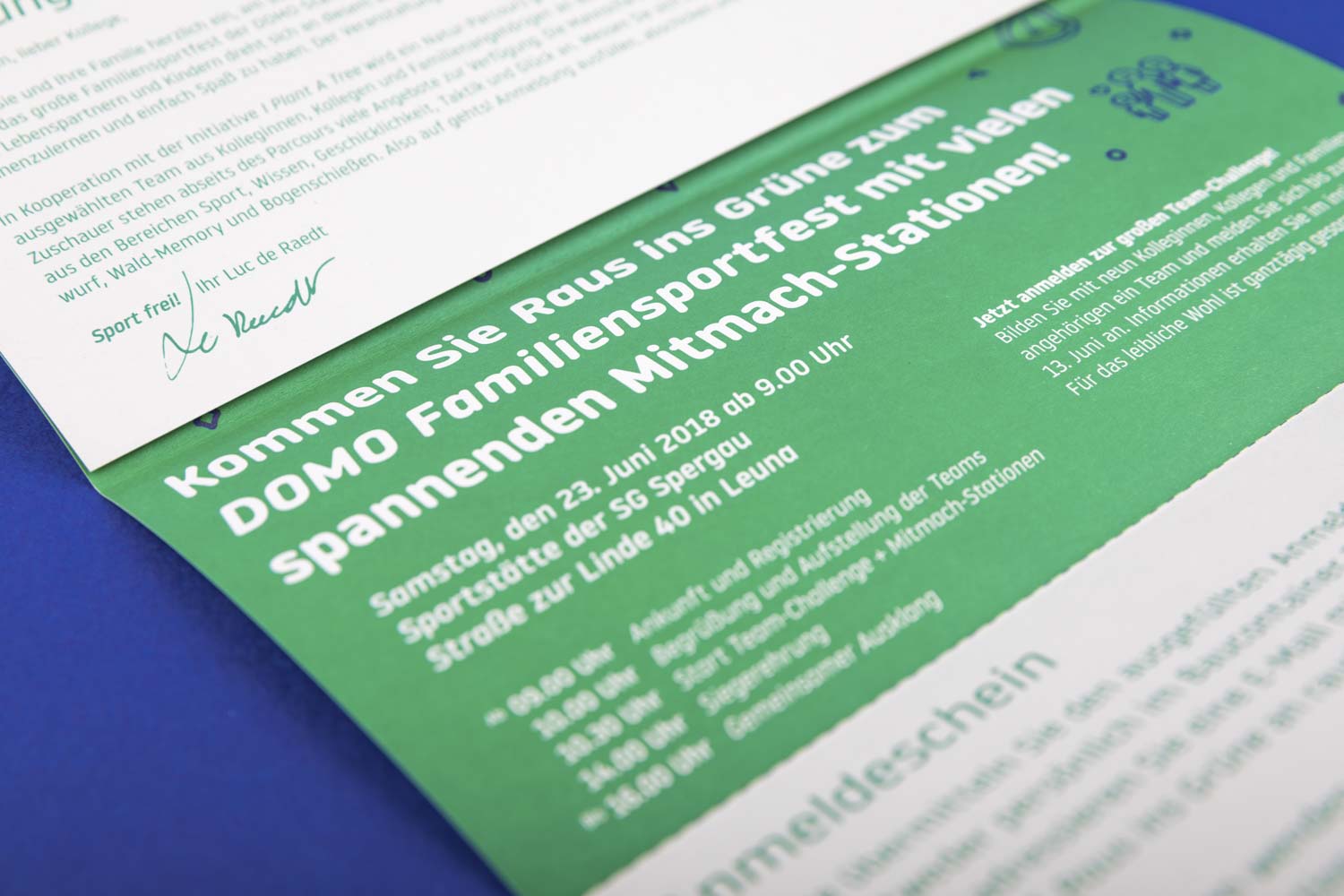 Eine Save-the-Date Karte in einer Nahaufnahme für das DOMO-Familien-Sportfest auf blauen Hintergrund.