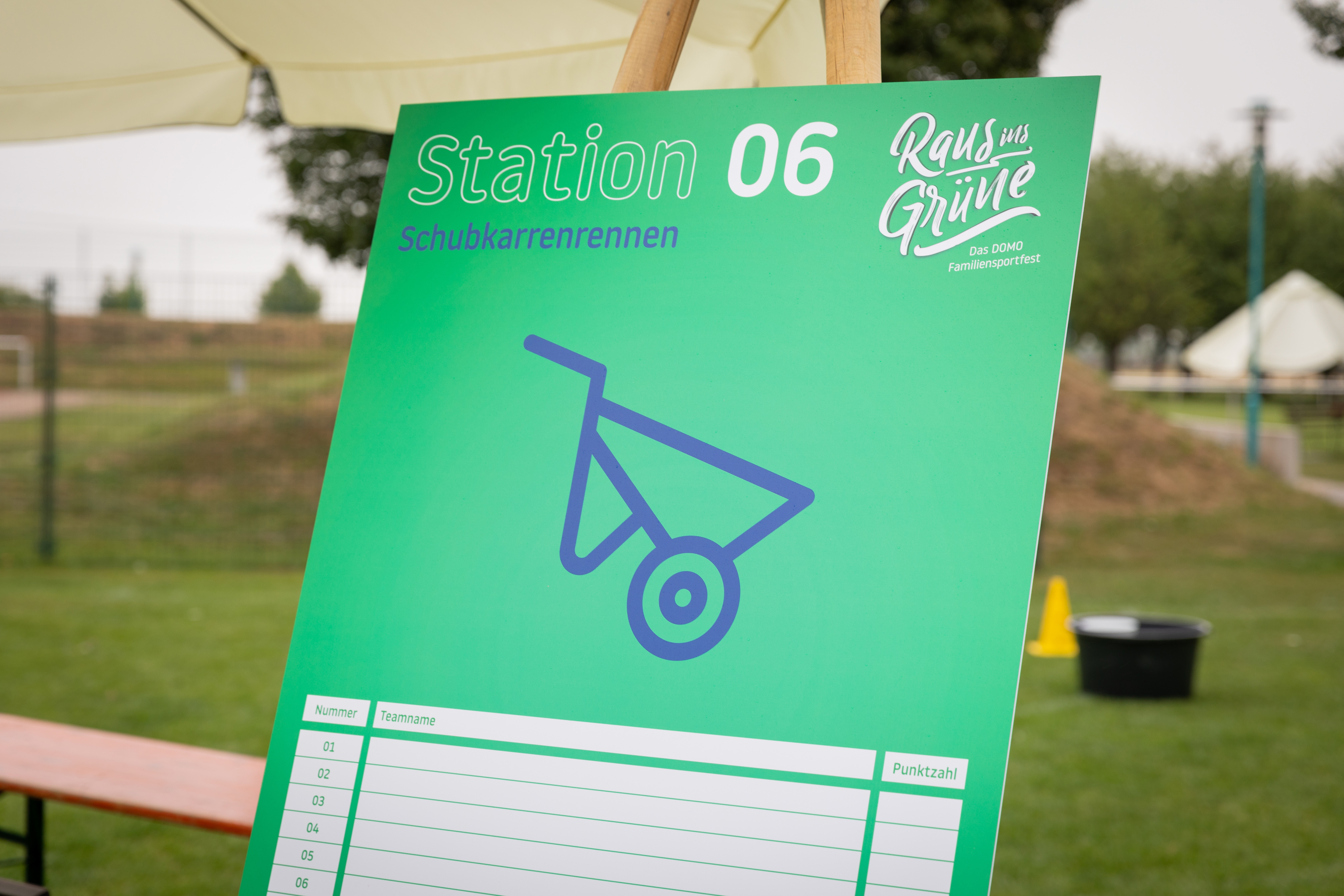 Zur Wegeleitung dient ein großformatiges Event-Plakat, das Station 6 markiert. Hier findet ein Schubkarrenrennen statt.