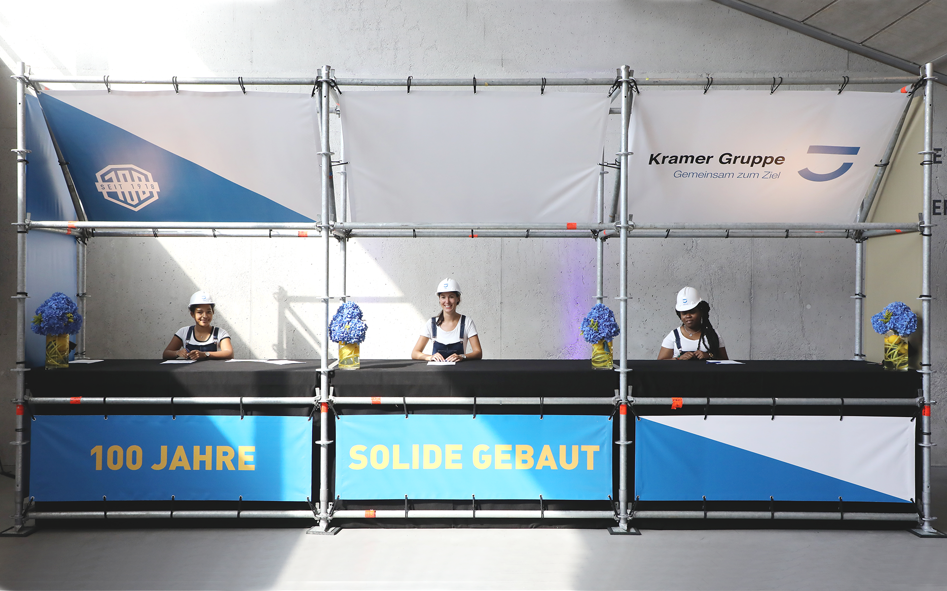 Die Akkreditierung wurde mit Hilfe von Baugerüst-Elementen aufgebaut und im Event-Design gestaltet. Die Empfangshostessen trugen, entsprechend der Gästeschaft aus der Baubranche, Bauhelme und Latzhose.