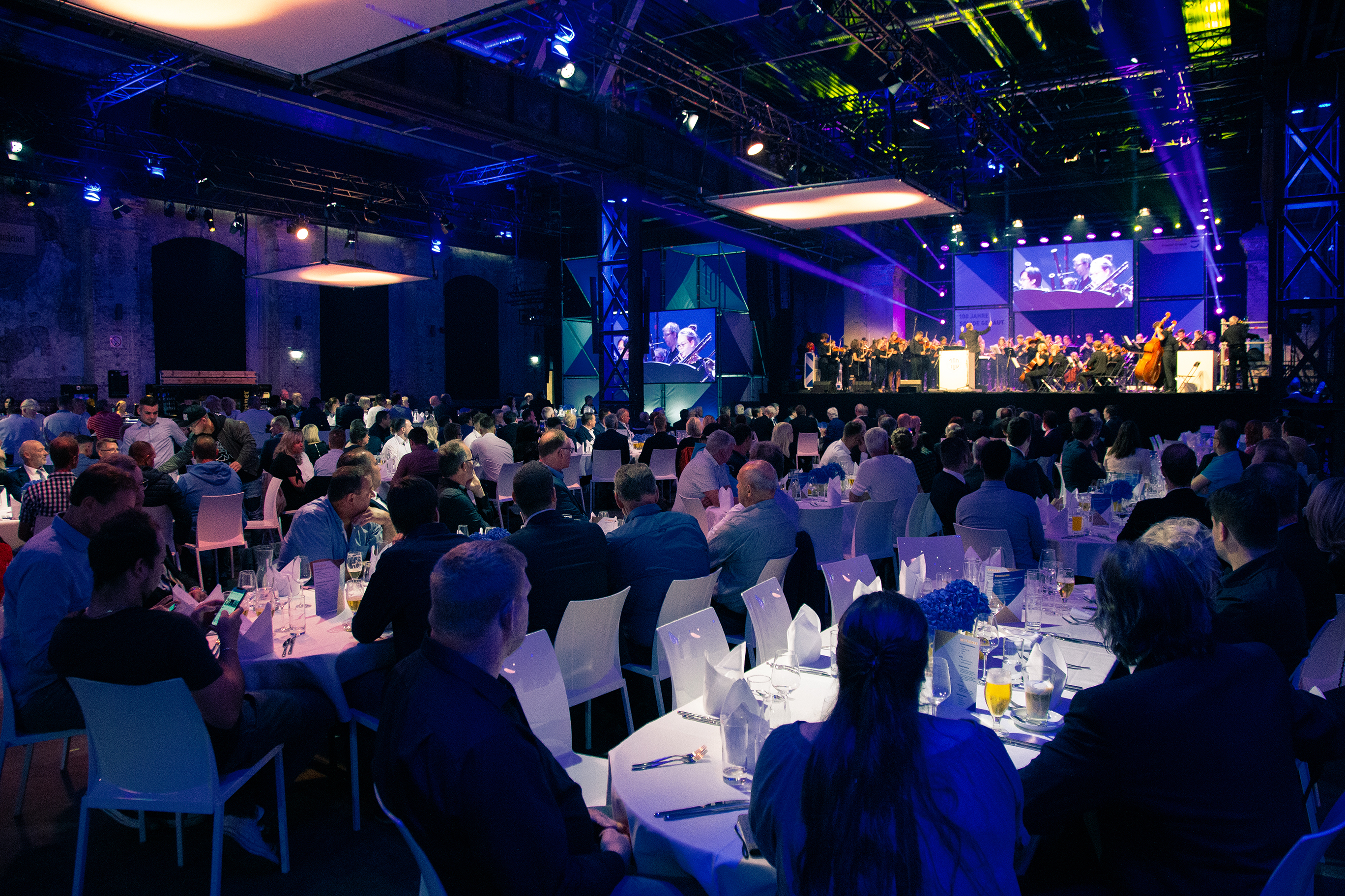 In der Warsteiner Music Hall sitzen 500 geladenen Gäste der Kramer Gruppe an Banketttafeln und schauen gespannt dem Jugendsinfonieorchester zu.