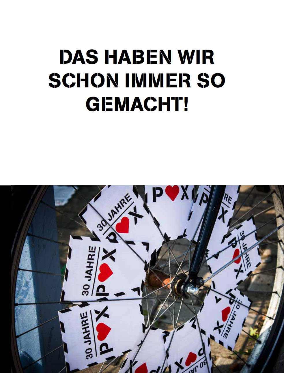 Postkarten mit dem Veranstaltungsslogan „30 Jahre POX“ sind in die Speichen eines Fahrrads eingeklemmt.
