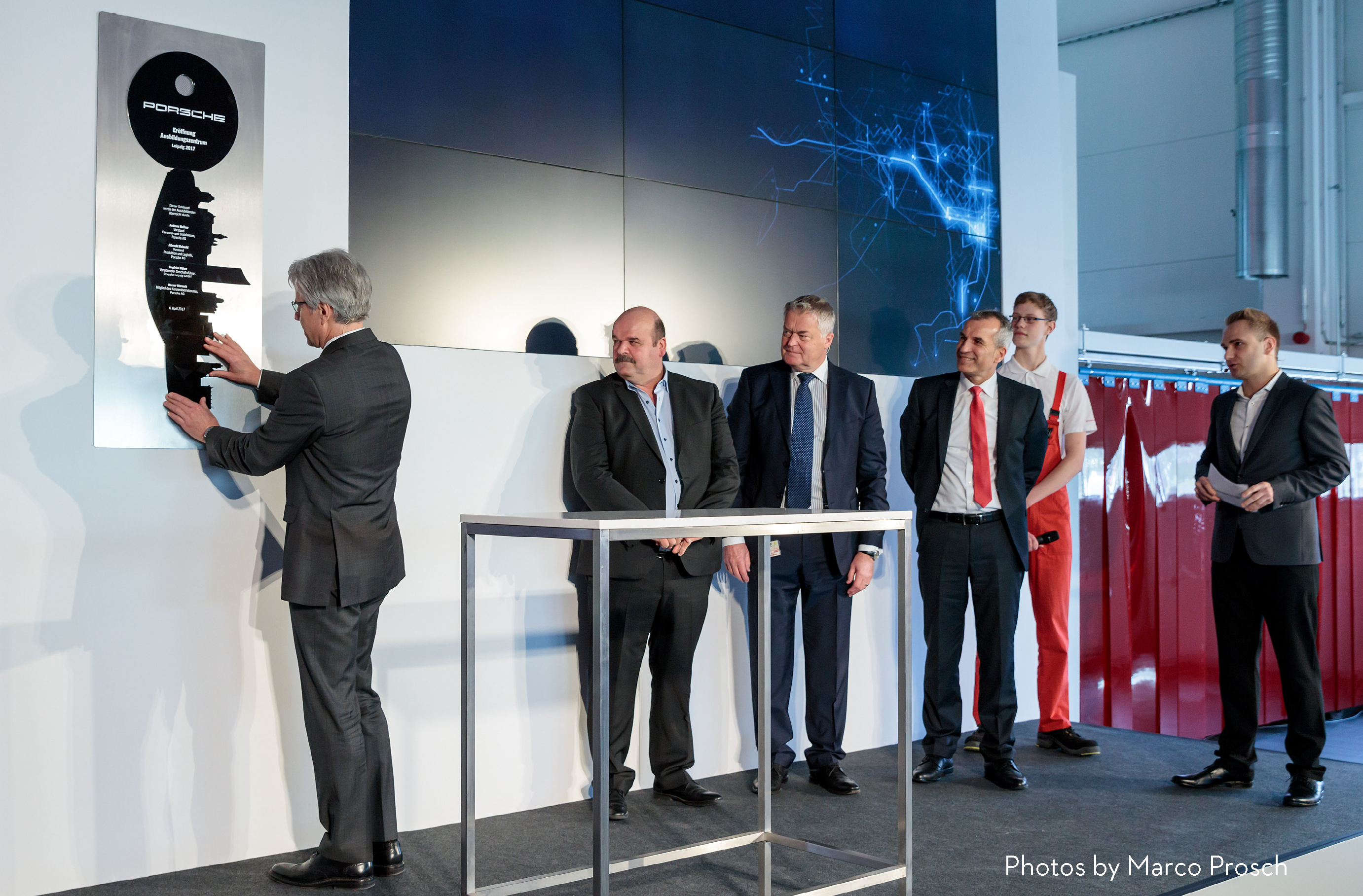Auf der Bühne wird ein symbolischer Schlüssel aus mehreren Teilen zusammengesetzt, welcher die Eröffnung des Ausbildungsstandortes Leipzig symbolisiert. Dabei stehen vier Redner, der Moderator Jan Kaufhold und ein Asuzubildender auf der Bühne.