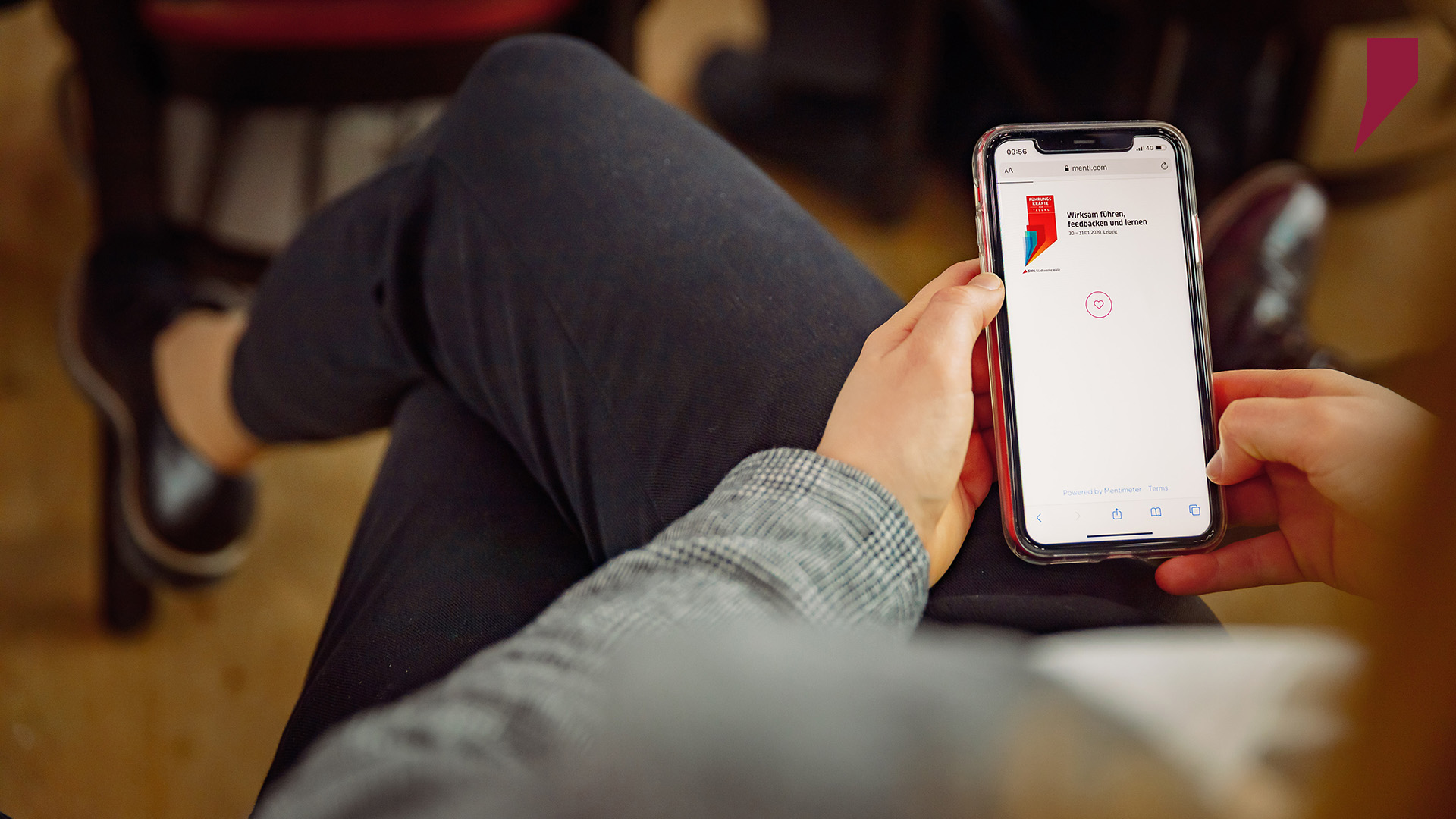 Eine Mitarbeiterin nutzt das interaktive Voting Tool einer WebApp, um  Feedback und Fragen an die Geschäftsführer auf der Bühne zu richten.
