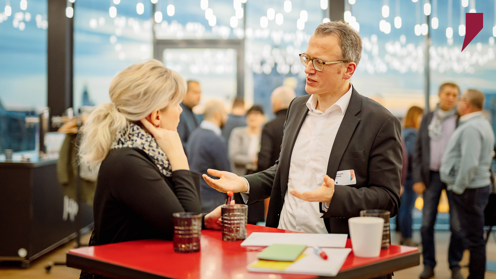 Im Vordergrund stehen zwei SWH-Führungskräfte ins Gespräch vertieft, während im Hintergrund eine größere Gruppe die Kaffeepause gemeinsam verlebt.